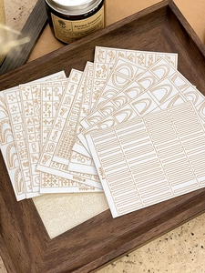 Macro shot of assorted golden nail art decals with star and moon patterns on a wooden tray