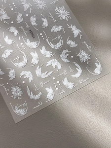 Vue macro d'autocollants pour ongles à fleurs blanches et motifs de feuilles botaniques