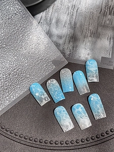 Détail de faux ongles bleus aux motifs de vagues marines en forme de trapèze