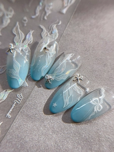 Détail d'ongles dégradés bleu clair avec relief 3D queue de sirène et perles brillantes