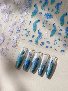 Close-up of peacock nail art stickers with laser holographic feathers and cloud patterns