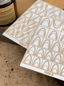 Detail of YITU gold geometric arch nail stickers with minimalist lines on dark background