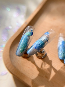 Macro view of blue and silver peacock feather nail stickers with silver glitter finish