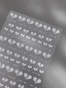 Nahaufnahme von 3D-geprägten silbernen Herz-Nagelaufklebern mit Glitzer und Love-Schriftzug