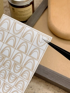 Detailed view of gold geometric nail stickers with tweezers for easy application