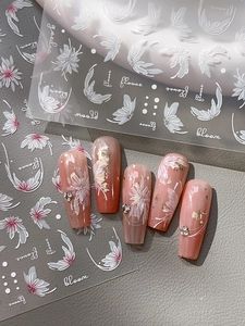 Détail macro de faux ongles dégradés rose nude avec relief floral blanc 3D et feuilles d'or