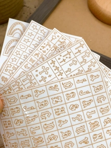 Macro shot of gold metallic nail stickers featuring gothic alphabet and cosmic symbols