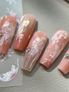 Détail macro de stickers pour ongles à fleurs blanches avec feuille d'or et cristaux