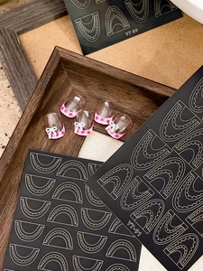 Detail of pink plaid nail stickers with 3D bows and wave patterns on a wood frame