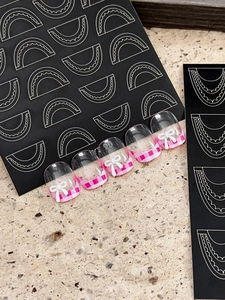 Close-up of pink and white checkered press-on nails with 3D white bow tie decorations