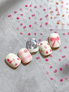 Dettaglio di adesivi per unghie floreali con perle 3D, fiocchi rosa e paillettes cuore