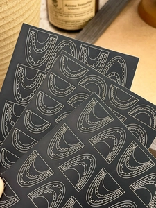 Detail of bohemian lace nail art stickers with silver geometric arches on black background