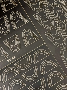 Detail showing white geometric wave patterns on black lace-style nail art stickers
