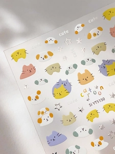Detail view of silver-foiled cartoon cat and star nail art stickers with cute designs
