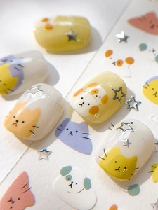 Macro detail of 3D embossed nail stickers featuring cute cartoon cats and silver stars
