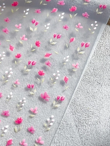Primo piano di adesivi per unghie con fiori rosa e bianchi su base opaca e traslucida