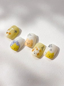Macro detail of yellow cat nail art stickers with silver stars and cute hand-drawn patterns