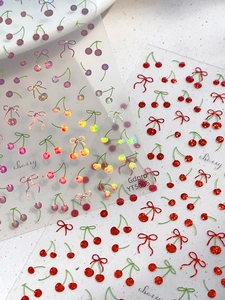 Dettaglio macro di adesivi per unghie con ciliegie e fiocchi laser olografici e glitter
