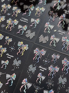 Close-up of glitter laser bow and ribbon nail stickers with 3D star heart patterns