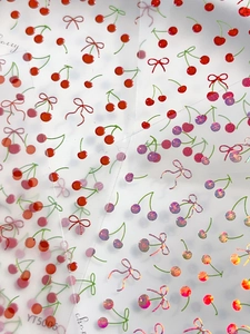 Vista macro di adesivi per unghie con ciliegie e fiocchi olografici lucidi