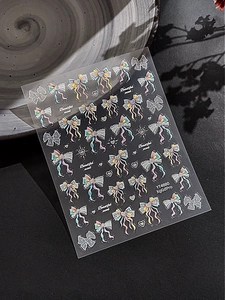 Detail of YT4880 nail stickers with iridescent bows and hearts on a ceramic plate