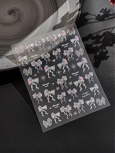Macro detail of laser iridescent bow and lace nail stickers with heart patterns