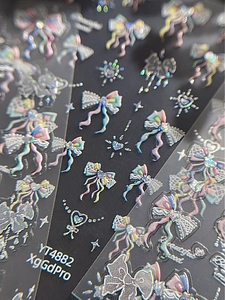 Detailed view of 3D holographic bow and heart nail art stickers with starlight effect