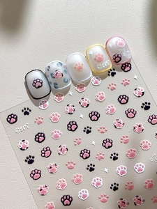 Macro detail of 3D cat paw nail stickers with embossed cat pad and letter designs