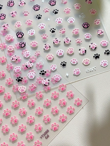Close-up of 3D embossed cat paw nail art stickers in pink and white textures