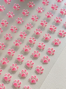 Macro view of 3D embossed pink cat paw nail art stickers with glossy resin texture