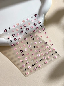 Detailed macro view of 3D embossed cat paw nail art stickers with pink and black patterns