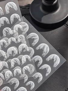 Detailed relief texture of white pleated lace nail art stickers on a grey background