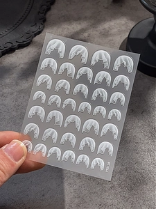 Detailed view of white embossed lace nail art stickers with textured floral patterns
