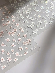 Macro shot of 3D embossed floral nail stickers featuring pearlescent white petals