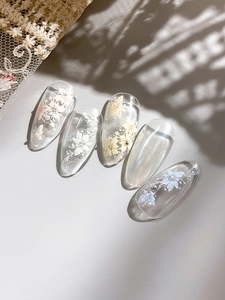 Detailed view of floral press-on nails with 3D pearl accents and artistic flower designs