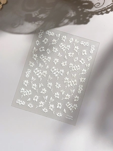 Detail of 3D embossed white flower and butterfly nail art stickers with relief texture