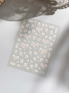 Macro detail of cherry blossom and butterfly nail art stickers on a matte backing