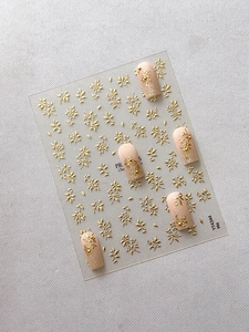 Makroaufnahme von 3D-Präge-Nagelaufklebern in Gold mit filigranen Blumenmustern