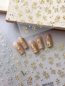 Detaillierte Nahaufnahme von metallischen 3D-Nagelaufklebern in Gold und Silber