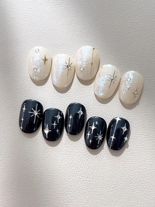 Détail de faux ongles faits main avec motifs d'étoiles argentées et strass brillants