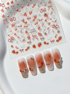 Detail view of strawberry and bow nail stickers with finished gradient pearl manicure