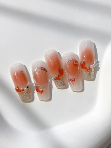 Macro detail of gradient blush nail stickers with red 3D bows, pearls and strawberry charms