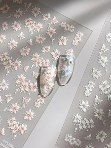 Macro view of 3D embossed floral nail stickers showing white cherry blossom and butterflies