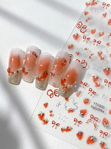 Close-up of strawberry and bow nail stickers applied on almond shape gradient nails