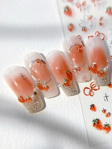 Macro detail of peach gradient press-on nails with 3D strawberry and bow art stickers