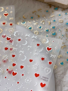 Détail d'autocollants nail art avec motifs de soleil, lune et cœurs dorés