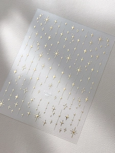 Gros plan sur des autocollants pour ongles argentés avec motifs d'étoiles dorées