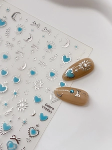 Détails macro de stickers nail art cœur bleu métallisé et lune étoile argentée sur feuille