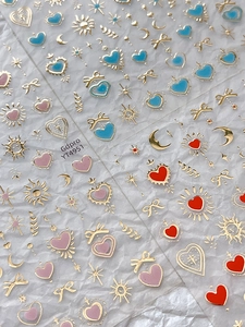 Détail d'autocollants pour ongles lune et étoiles avec contours dorés et motifs de cœur