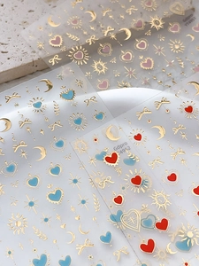 Détails macro d'autocollants nail art avec motifs de cœurs, lunes et étoiles dorés